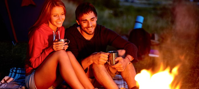 Young couple sitting on the ground and drinking tea while lookin